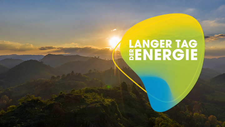 Das “Der Lange Tag der Energie”-Logo vor dem Hintergrund einer aufgehenden Sonne über einer steirischen Landschaft.